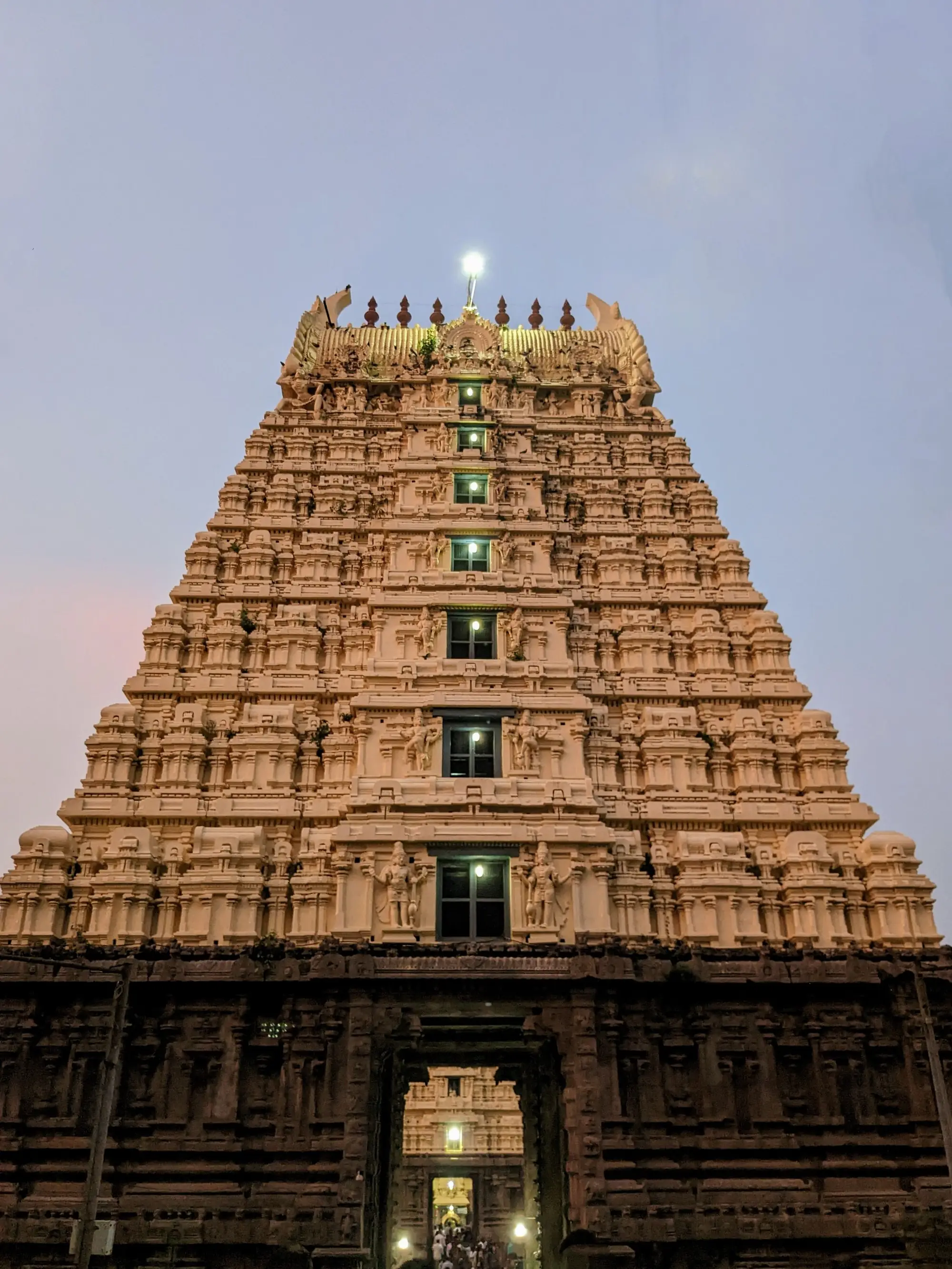 A temple gopuram at dusk with its doorway lit